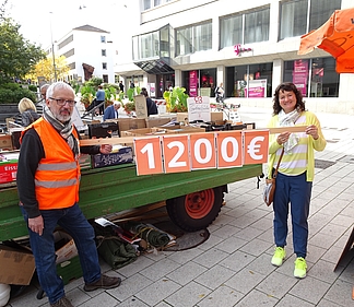 Sylvia Perl, zweite Vorsitzende des Fördervereins der Paul-Meyle-Schule und Uli Stein vom ÖDP Kreisverband Heilbronn vor einem Traktoranhänger mit Büchern 